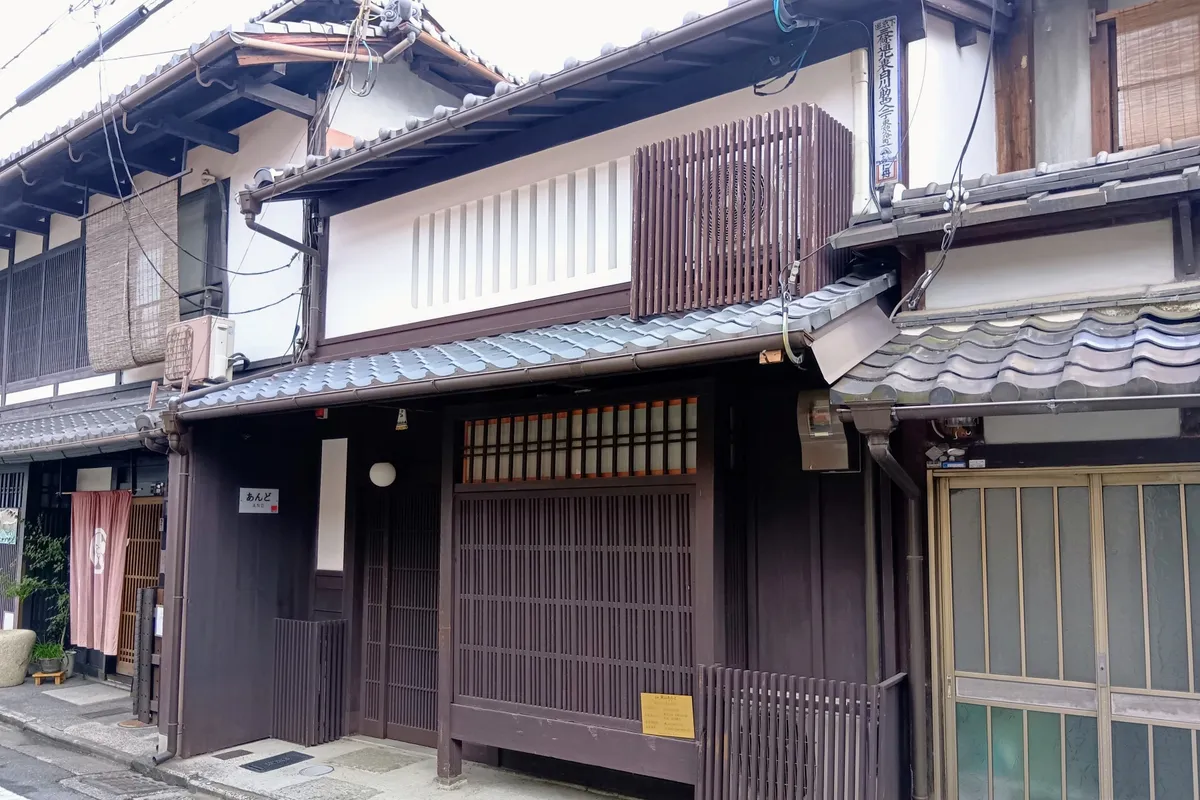 Street facade of And, with dark lattice doors and a white upper wall